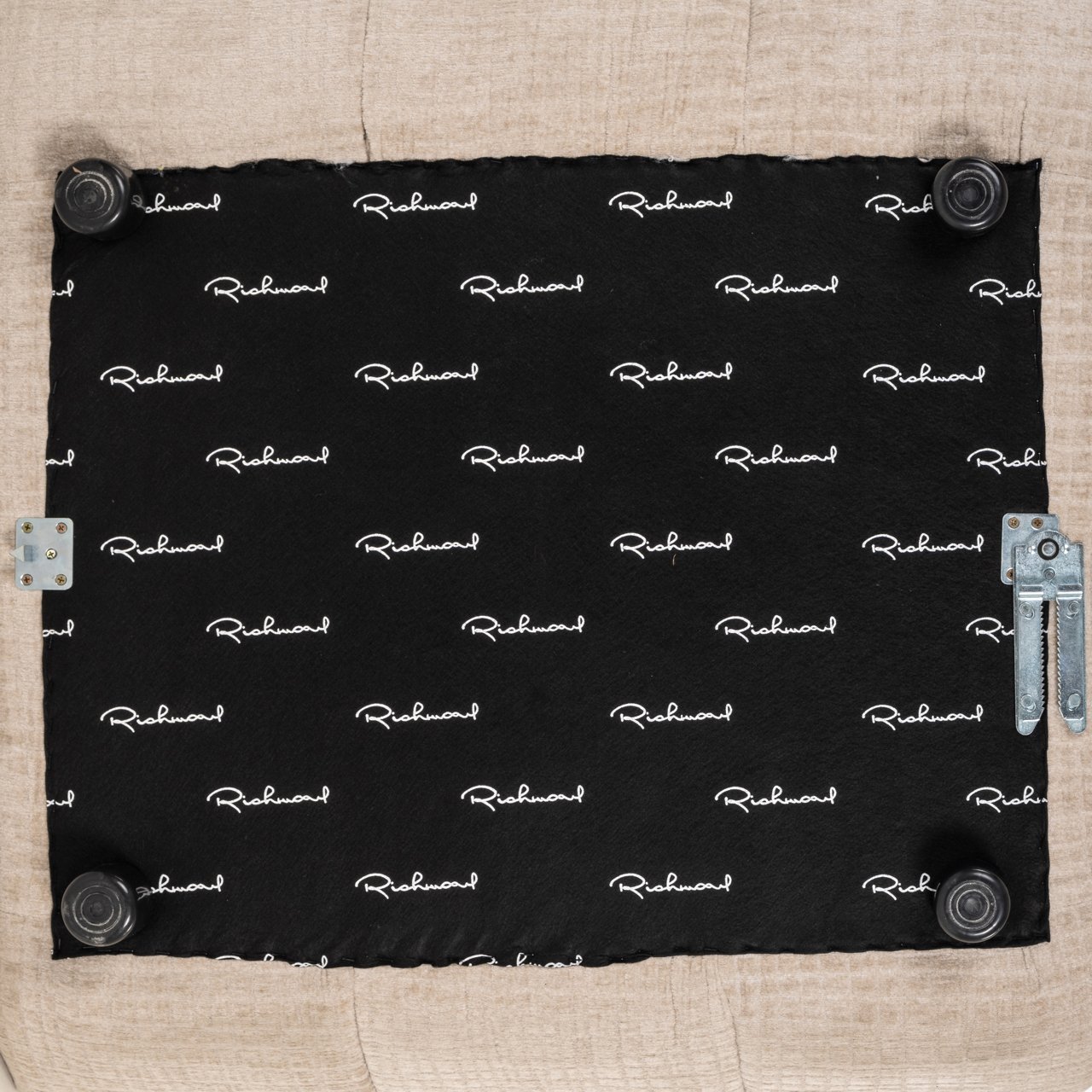 Spód siedziska z logowanym materiałem richmondinteriors i czarnymi kółkami meblowymi.